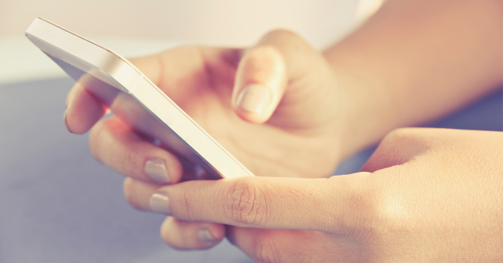 Hands holding a silver smartphone.