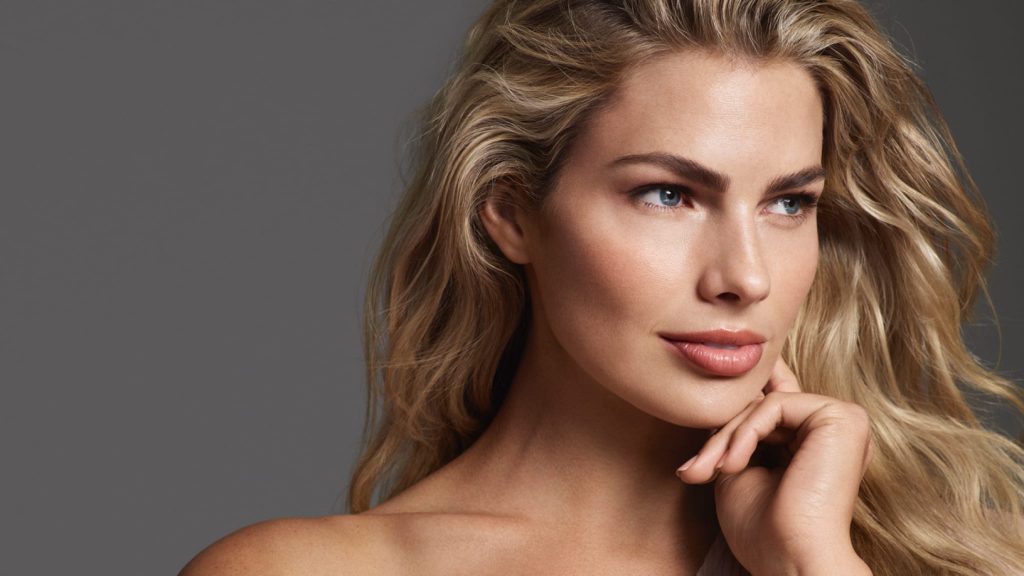 Close-up of beautiful woman with bare shoulders and long, flowing blonde hair looks off-camera