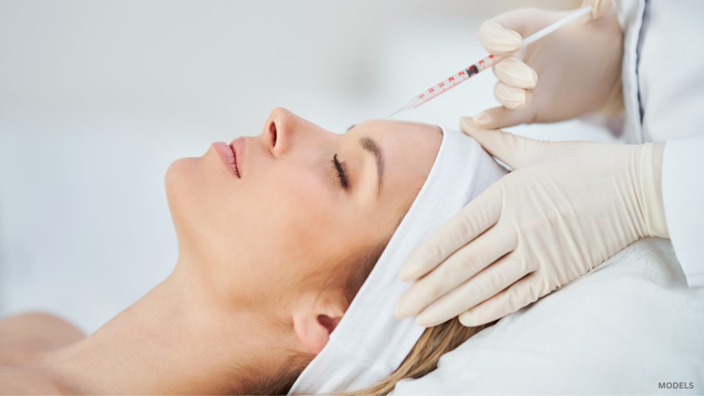 Woman receiving injectable treatment from doctor (models)