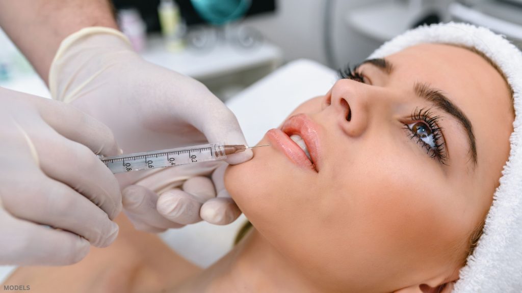 Woman receiving injectable lip treatment (model)