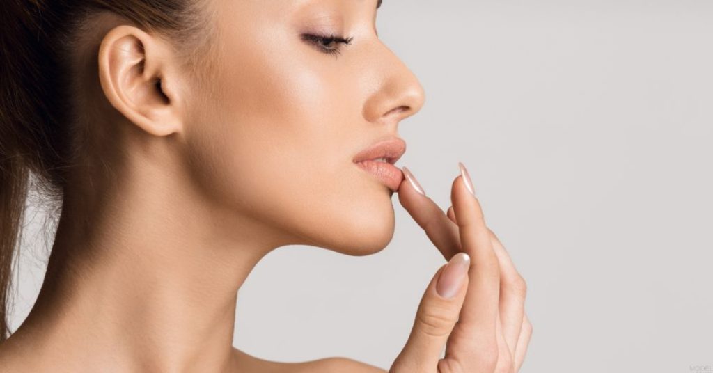 Woman touching her lips with finger (model)