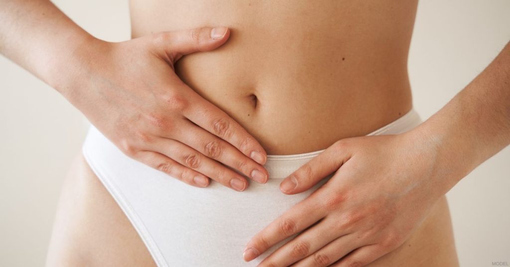 Female figure (model) with hands over abdominal and belly button after a tummy tuck